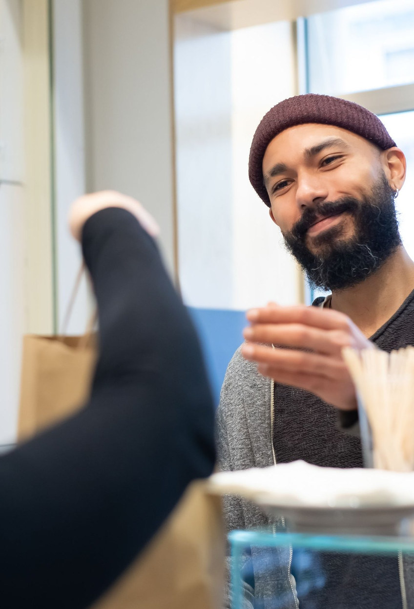 A barista greets a customer he recognises while her usual order is being made.