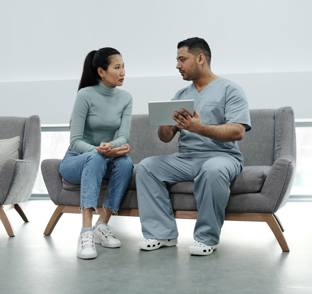 A clinician goes through a treatment plan on a tablet while the patient listens and considers it.