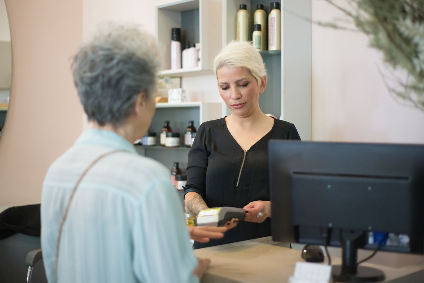 A client at the salon counter at the end of a familiar visit.
