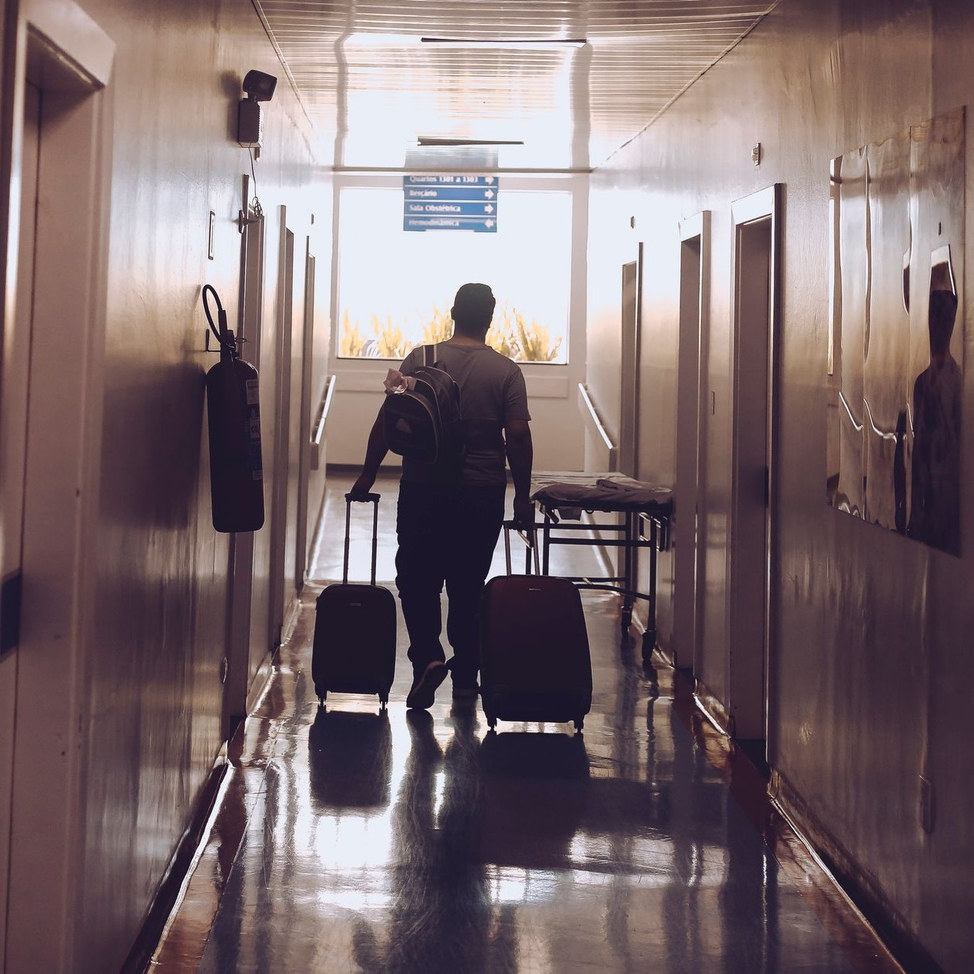 A guest wheeling luggage down a hotel corridor at the end of a stay.