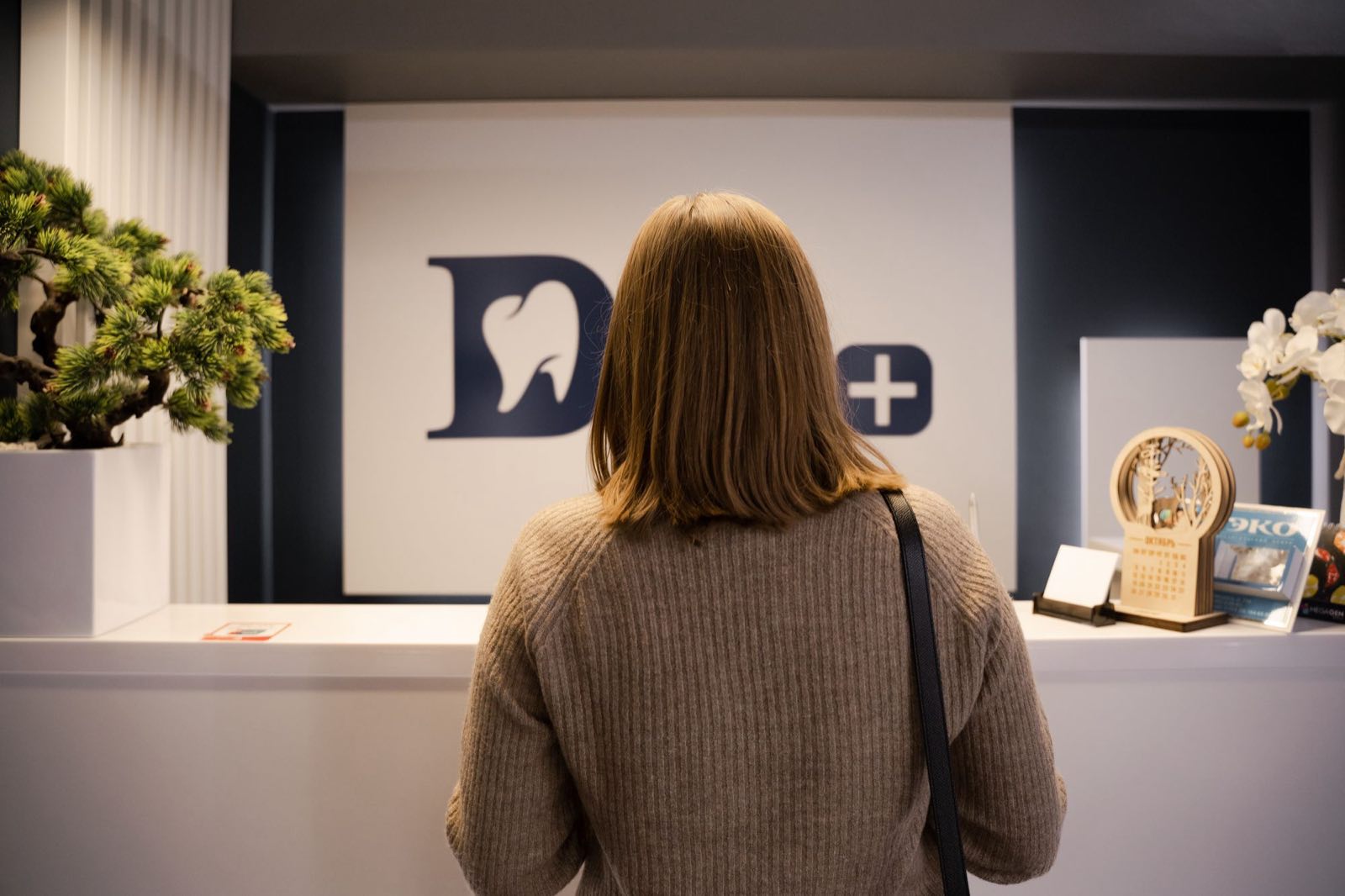 A patient waiting at a dental practice reception, seen from behind.