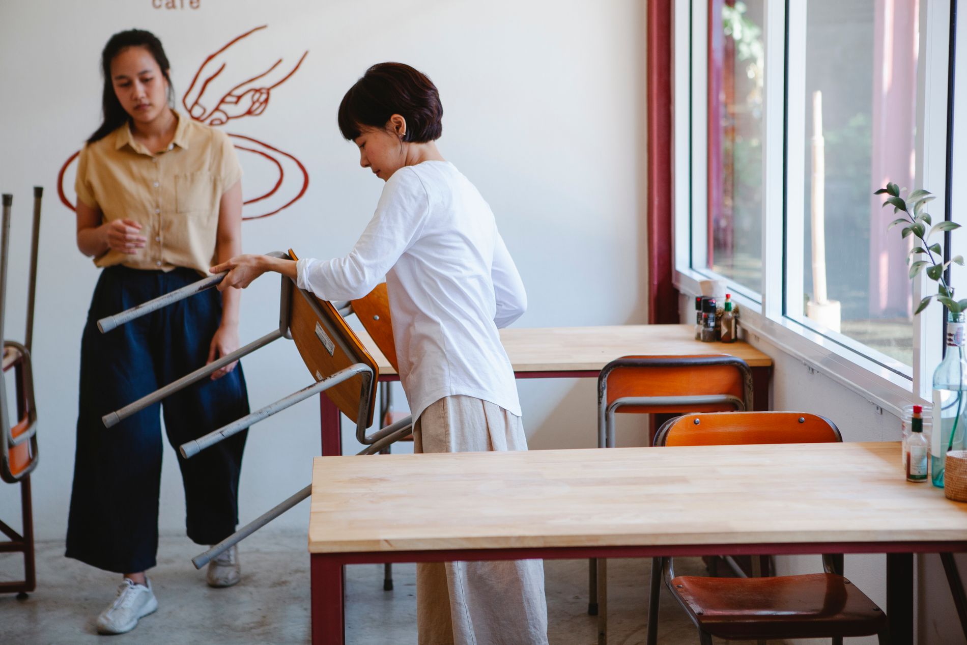Two staff members setting the tables and chairs before service.