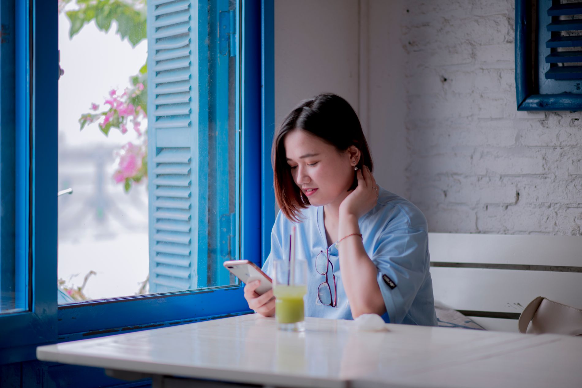 A customer alone at a café table, reading something on her phone.