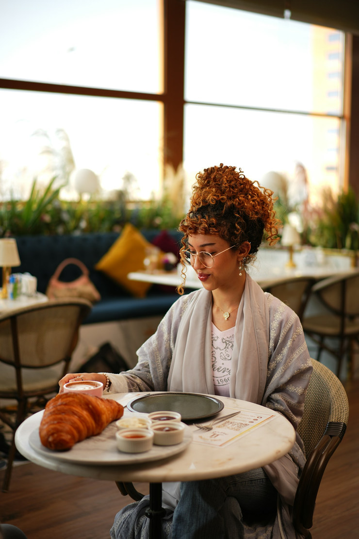 A regular at breakfast, at ease, her usual table.