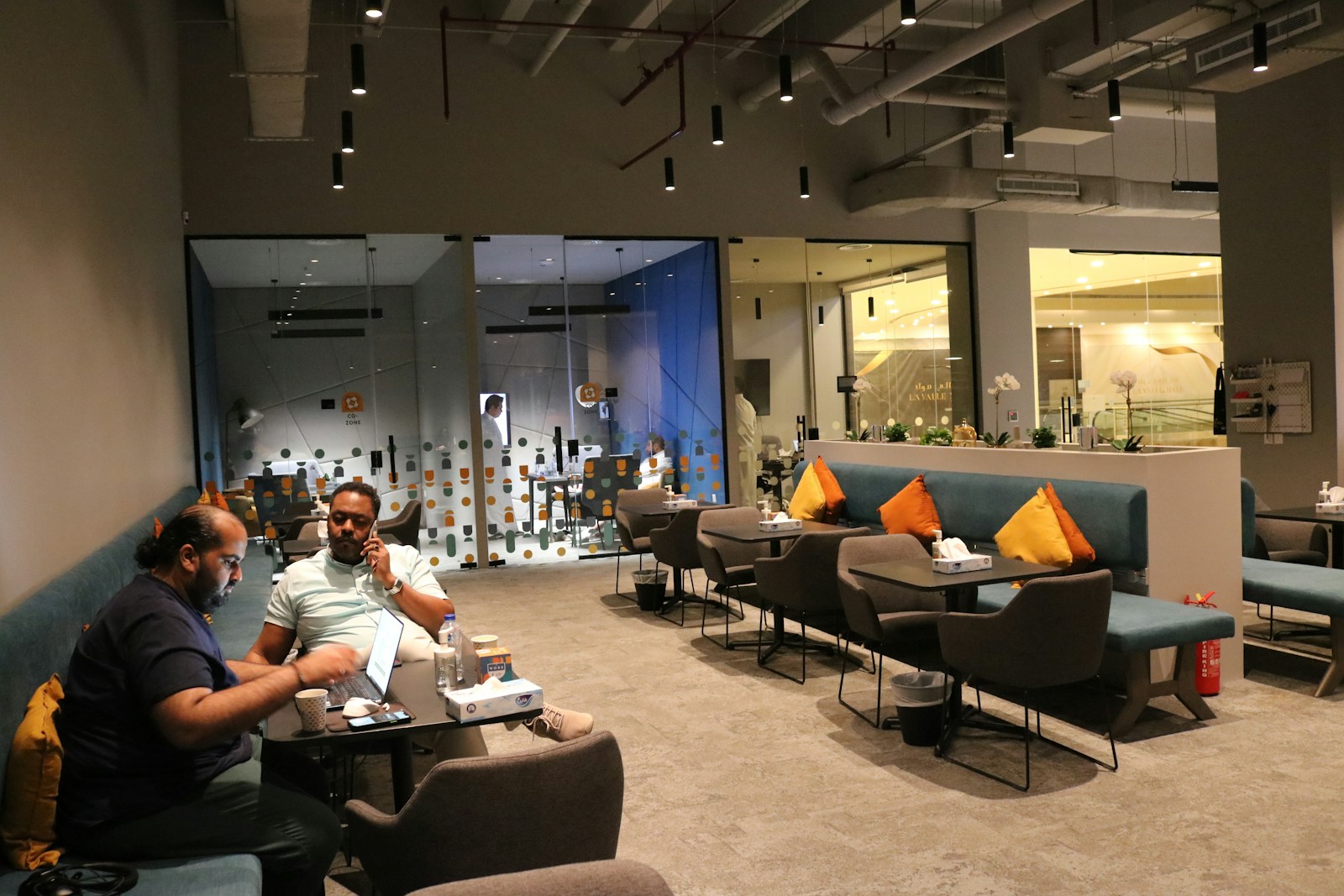 Two people in conversation across a table in a Riyadh lounge.
